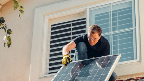 Mann auf dem Dach mit Photovoltaik-Element